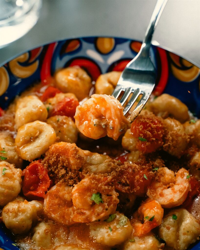 Dettaglio di gnocchi con gamberi, pomodorini e crumble croccante da Serenata
